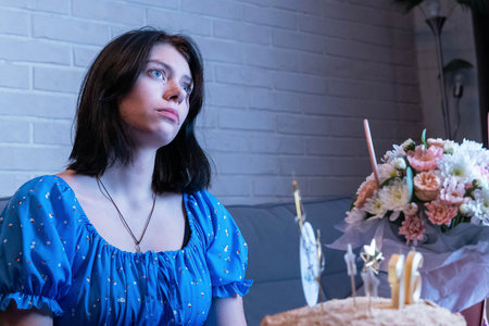 Sad pensive young woman celebrating her birthday alone at home