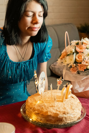 Young woman making a wish before blowing out candles on her sixteenth birthday cakeの写真素材