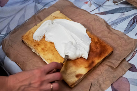 Pastry chef spreading cream on napoleon cake layers with spatulaの写真素材