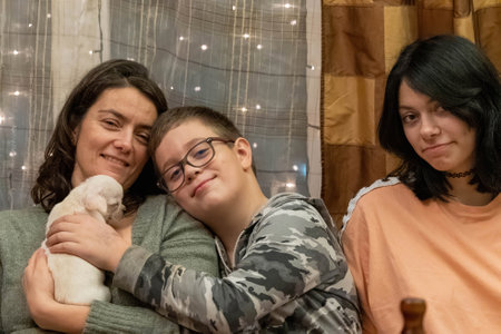 Mother and children are cuddling a puppy at homeの写真素材