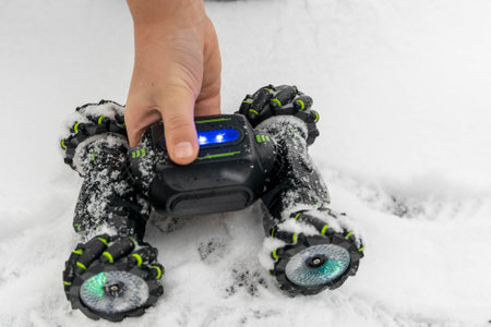 Kid holding a remote control car toy with led lights on snowy groundの写真素材