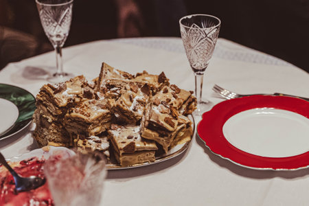 Sliced pieces of layered cake with nuts and chocolate sprinkles, served on a platter on table, ready for dessertの写真素材