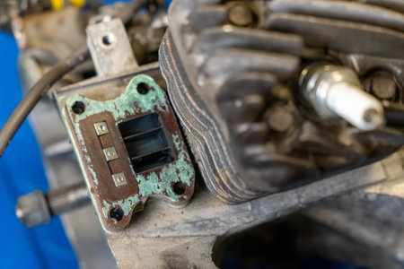 Close-up of a corroded reed valve block on a two-stroke engine, highlighting the effects of wear and tearの写真素材