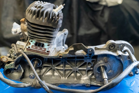 Motorcycle engine block with cylinder, piston, and other components, placed on a workbench, awaiting reassemblyの写真素材