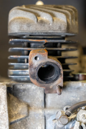 Old and rusty motorcycle engine cylinder with visible wear and tear, highlighting the exhaust port and cooling finsの写真素材