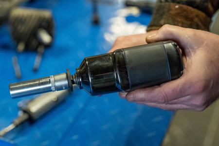 Close-up of mechanic holding an impact wrench with socket attached, ready for work in a vehicle repair shopの写真素材