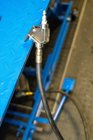 Close-up of a pneumatic hose coupling attached to a blue metal structure, potentially part of industrial equipmentの写真素材