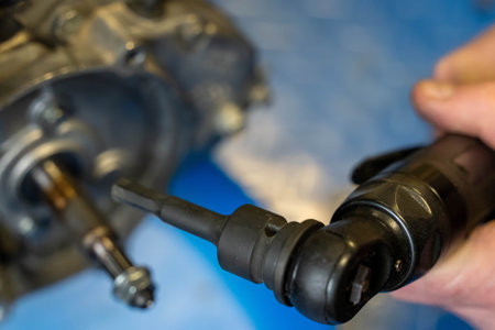 Close-up of a mechanic using a pneumatic wrench, tightening bolts on an engine part during maintenanceの写真素材