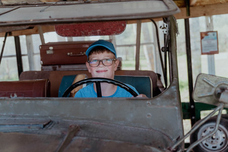 A child happily sits behind the wheel of a vintage car.の写真素材