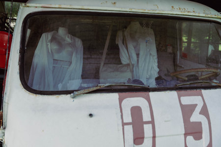 Mannequin figures in white cloths inside a deserted van at twilight.の写真素材