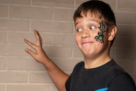 A colorful spider design painted on the cheek, accompanied by a playful expression and gesture.の写真素材