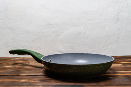 A frying pan is placed on a wooden table, ready for cooking or serving food.の写真素材