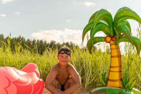 A joyful scene with inflatable toys including a palm tree decoration on a sunny beach dayの写真素材