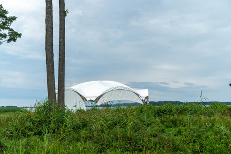 A white tent is positioned near the water's edge among greenery.の写真素材