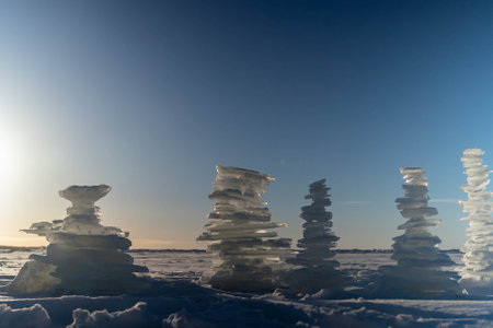 Ice cairns rising from frozen lake at sunset, winter landscapeの写真素材