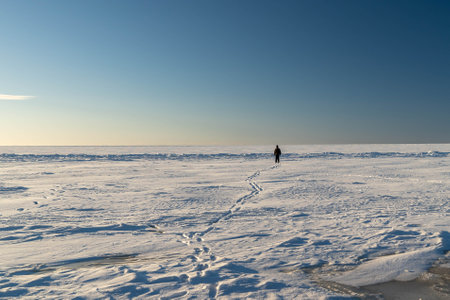 Lone explorer trekking across vast frozen lake in winter wonderlandの写真素材