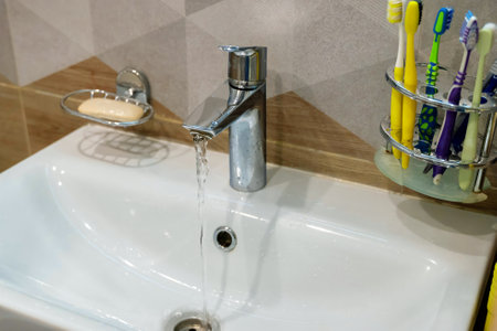 Water running from faucet into sink in modern bathroomの写真素材