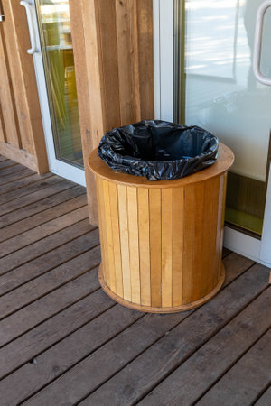 Round wooden trash can with black plastic bag outdoorsの写真素材