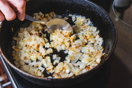 Chef frying diced onions in a pan on the stoveの写真素材