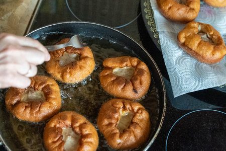 Cook frying belyashi in pan with oil on kitchenの写真素材