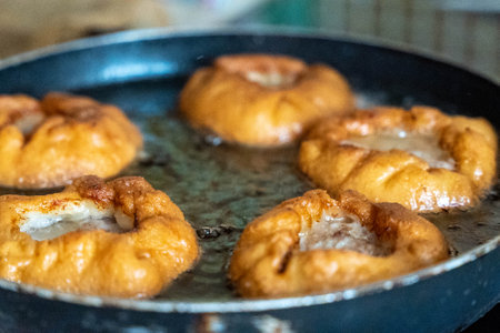 Deep frying doughnuts in a pan with hot oil, making doughnuts at homeの写真素材
