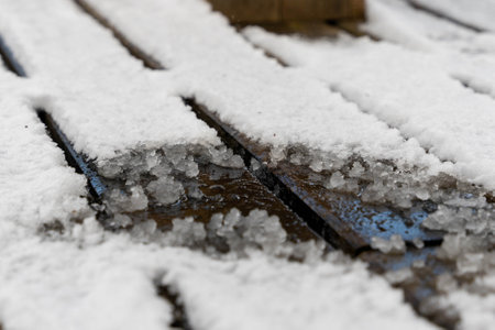 Melting snow on wooden deck creates icy surface in winterの写真素材