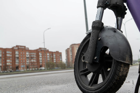 Electric scooter wheel standing on wet asphalt road after rain in cityの写真素材