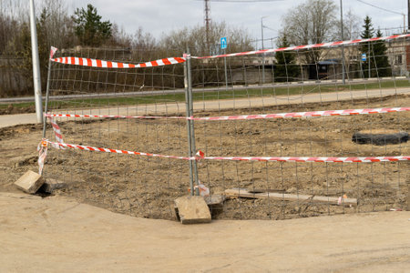 Red and white caution tape protecting construction site with metal fenceの写真素材