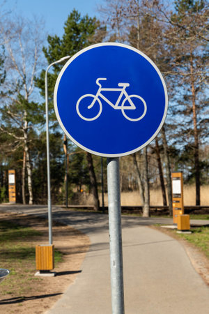 Blue bicycle lane road sign indicates bike path in city parkの写真素材