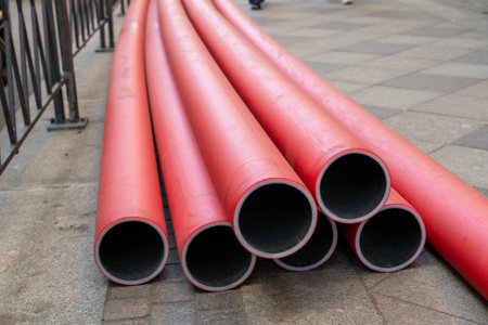 Red pre-insulated pipes laying on the sidewalk during city construction worksの写真素材