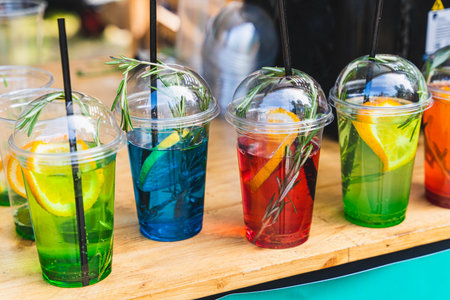 Colorful cocktails with straws and rosemary on wooden tableの写真素材