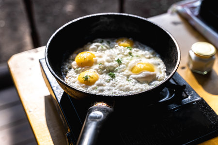 Fried eggs cooking in a pan on a portable stove