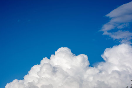 Bright white cumulus clouds drifting across a deep blue sky