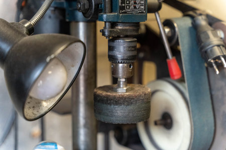 Polishing wheel mounted on drill press with lamp in workshop