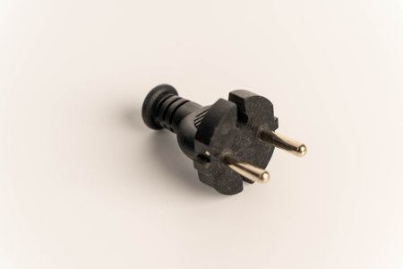 Black electric plug lying on a clean white background