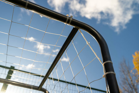 Soccer goal frame with netting against a bright blue sky, showcasing the structure and design of...