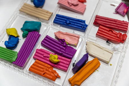 Colorful modeling clay pieces arranged in a clear plastic container, showcasing various vibrant hues and textures, ideal for creative projects and artistic endeavorsの写真素材