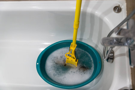 Cleaning tool submerged in a turquoise basin filled with soapy water, showcasing the process of...