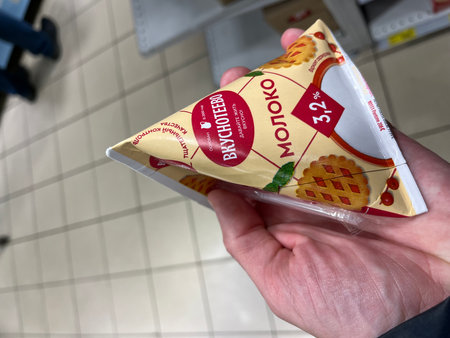 Russia, Sosnovy Bor, October 12, 2025 -A person holds a triangular dairy product package in a store aisleのeditorial素材