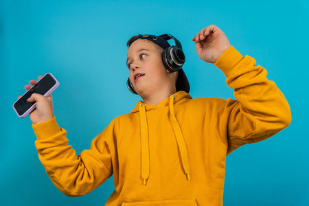 Boy dances while listening to music with headphones and holding a smartphone