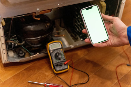 Home appliance repair in progress with tools and smartphone at kitchen