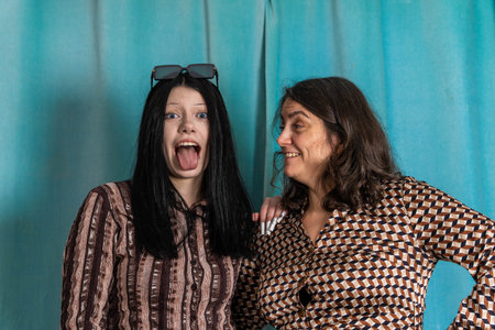 Women share a fun moment with playful expressions in a photo booth setting