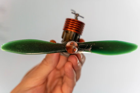 Hand holding a model airplane propeller with green blades and motor attachedの写真素材