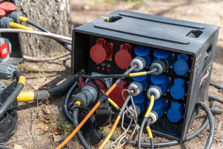 Electrical power distribution box with multiple outlets and cables connected, situated outdoors...