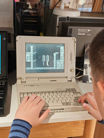 Russia, St. Petersburg, March 14, 2026 -Child plays classic video game on old Compaq laptop in...