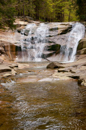 Cascading waterfall over natural rocks in forestの写真素材