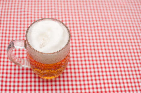 Glass Full of Beer on Table With Red Gingham Tableclothの写真素材