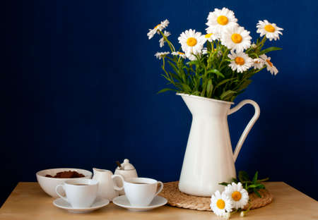 Coffee Mugs and Fresh Oxeye Daisies on wooden table in interior の写真素材