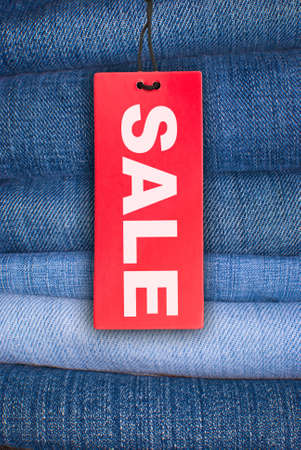 Red Sale Sign With Stack of Blue Jeans in Backgroundの写真素材