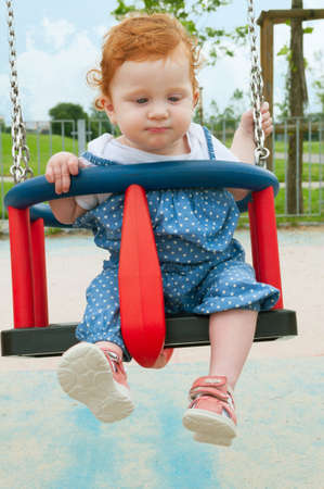 Happy Baby Girl Sitting in the Swingの写真素材
